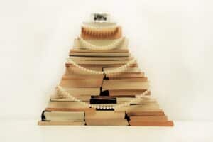 Bücher mit dem Buchblock nach vorne aufgestapelt zu einem Weihnachtsbaum mit Perlenketten