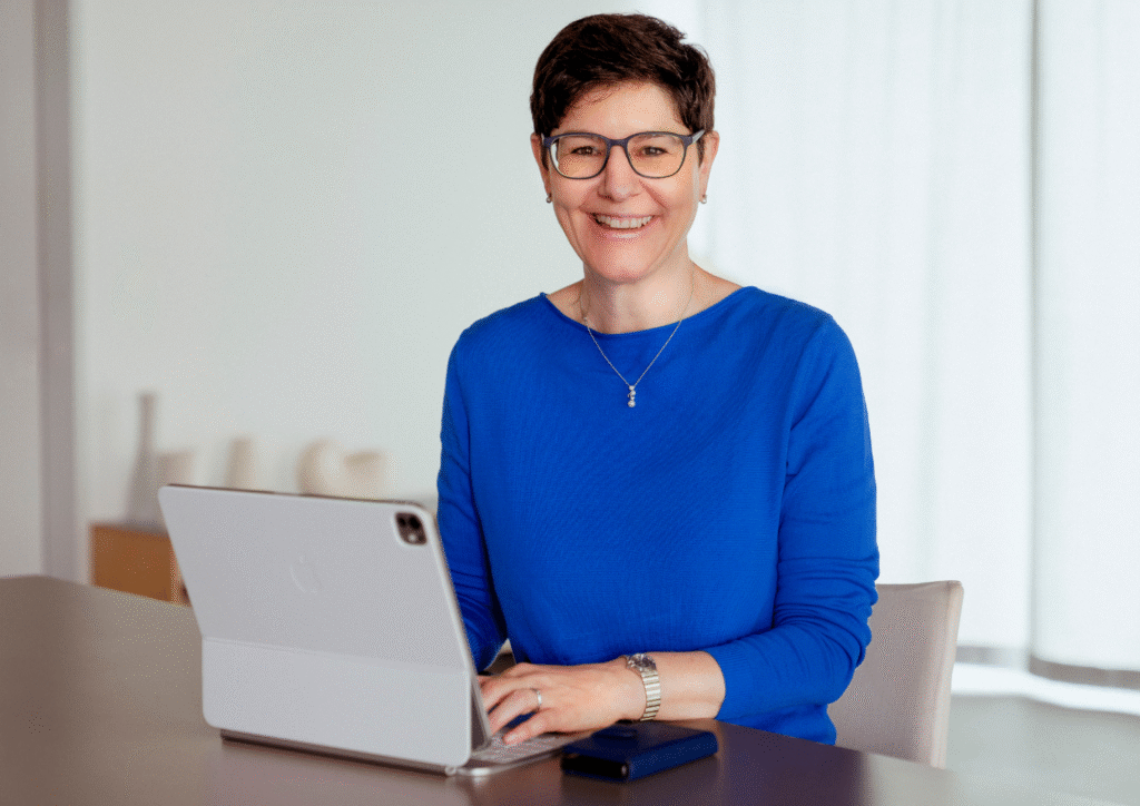 Ordnungscoach Karin Treichler sitzt an Ihrem Schreibtisch mit dem Laptop vor sich.