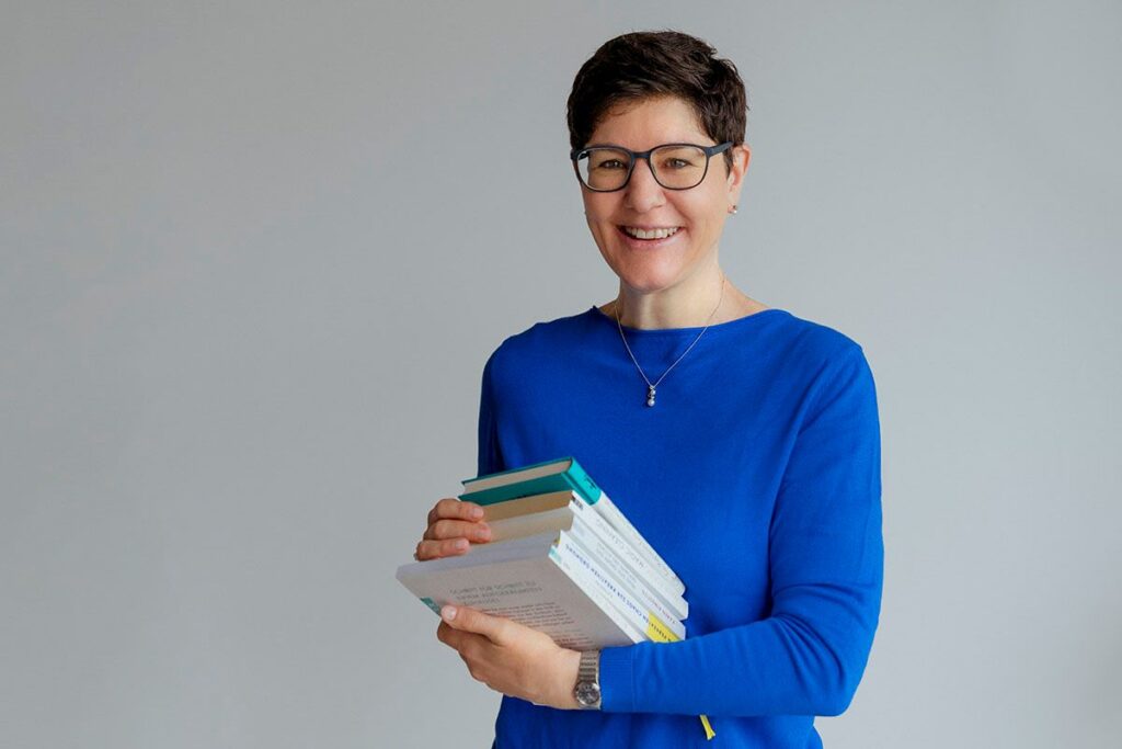 Aufräumcoach Karin Treichler in einem blauen Pullover hält fünf Bücher in den Händen.